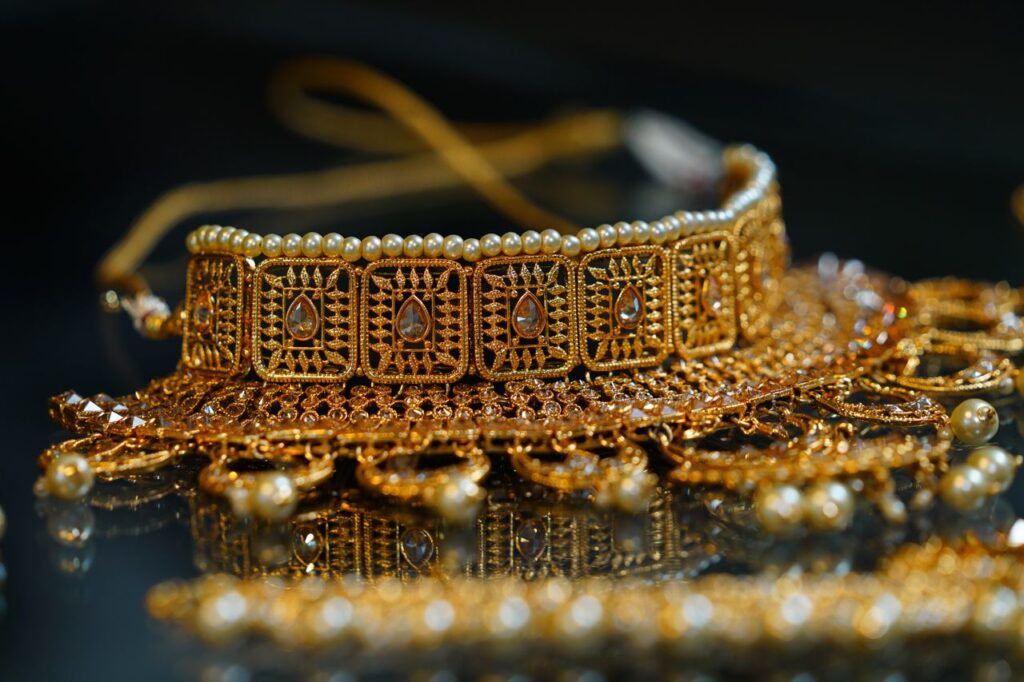 Stylish golden bracelet or necklace in oriental style decorated with pearls and crystals placed on black surface